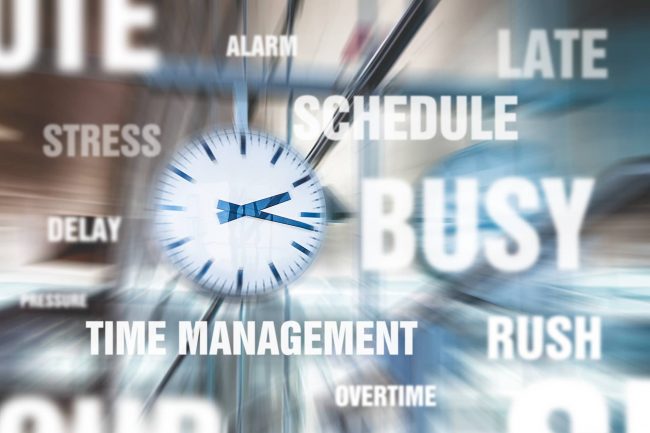 Workplace stress Blurry picture of clock with words stress, time management, schedule, busy, rush, delay, late, overtime around it